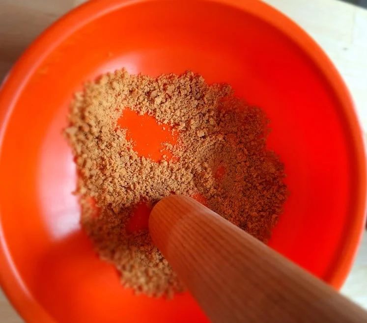 Digestive biscuits being crushed into fine crumbs with a rolling pin for the cheesecake base