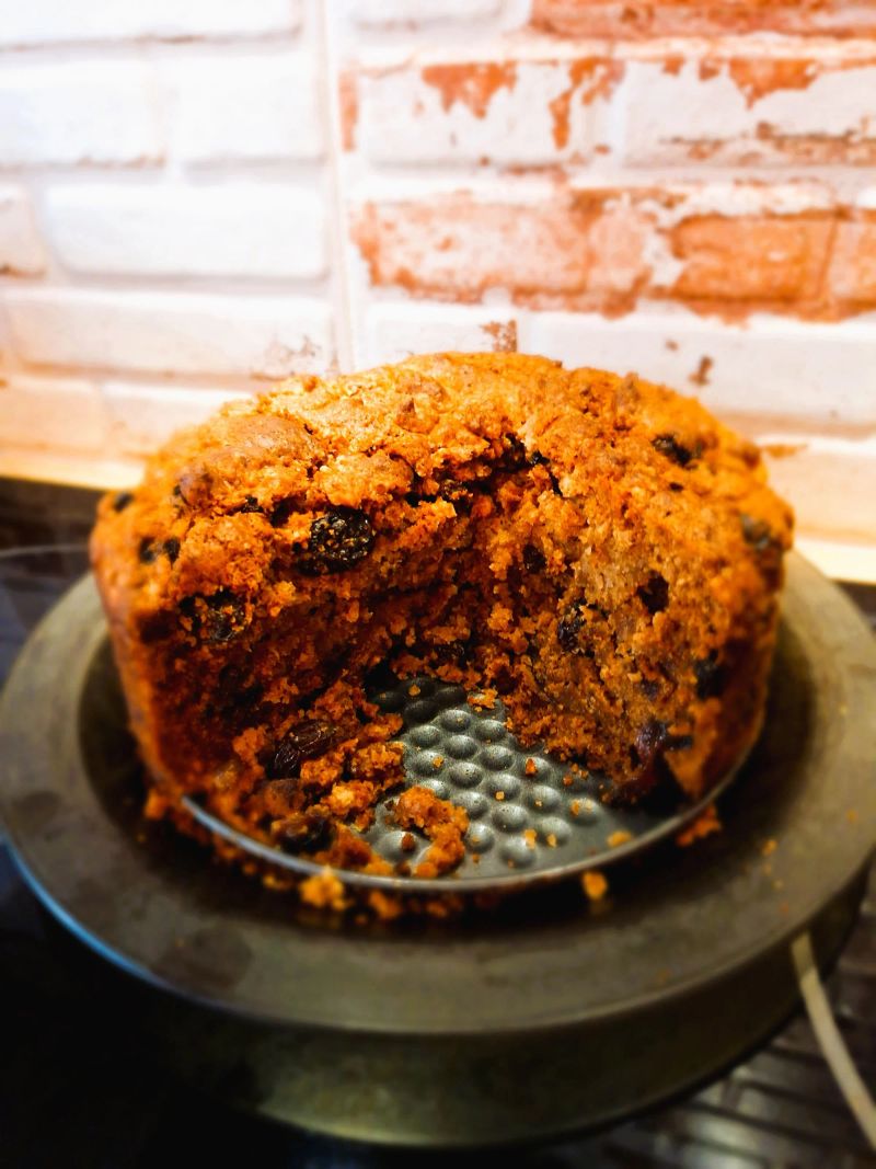Round whiskey tea cake with a slice removed, revealing the fruit-filled centre