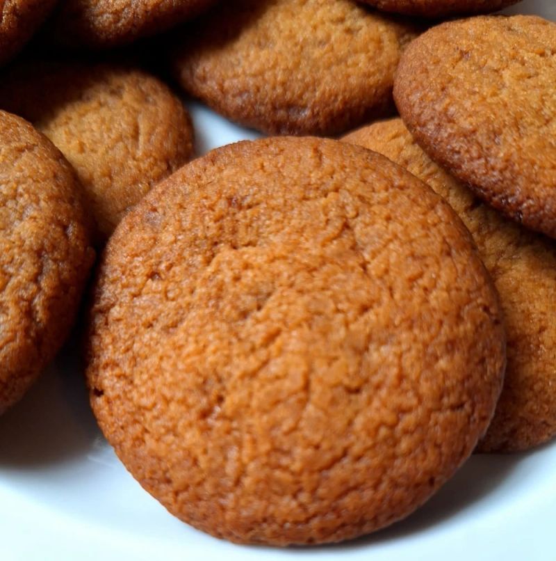 Close-up of homemade ginger nut biscuits, showing their golden-brown colour and crisp, crunchy texture.