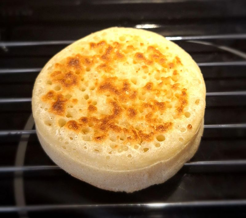 Freshly cooked homemade English crumpet with a golden, hole-filled surface