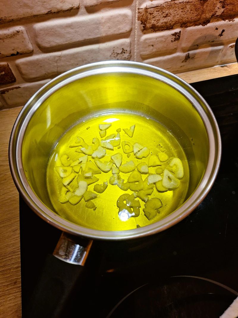 Sliced garlic gently heating in extra virgin olive oil
