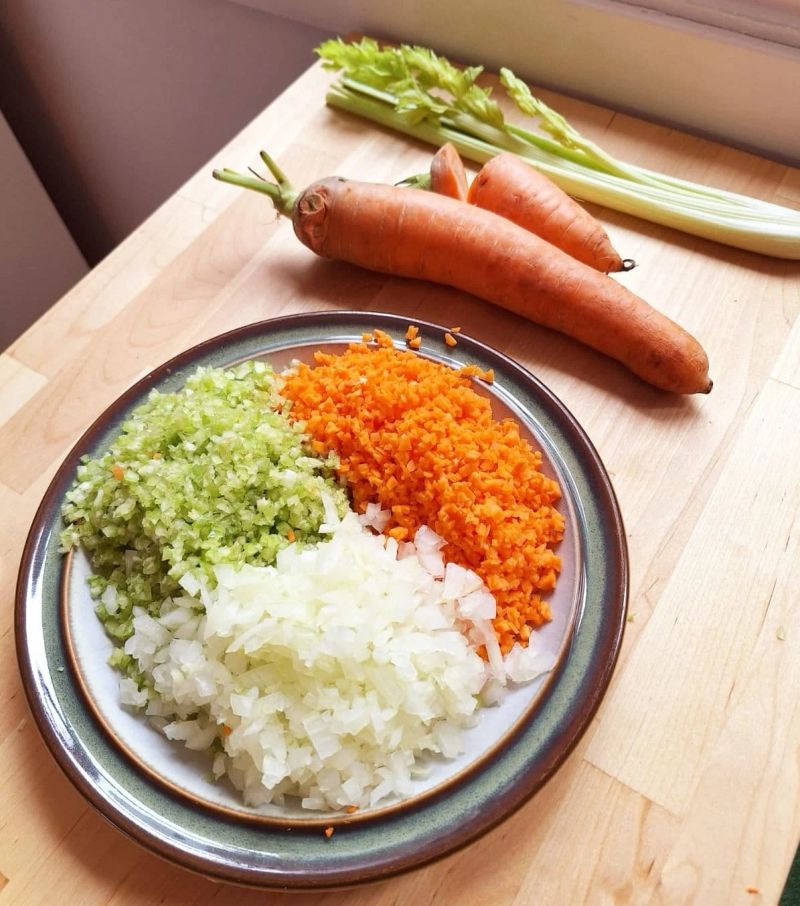 Finely chopped carrot, celery and onion beside the whole vegetables