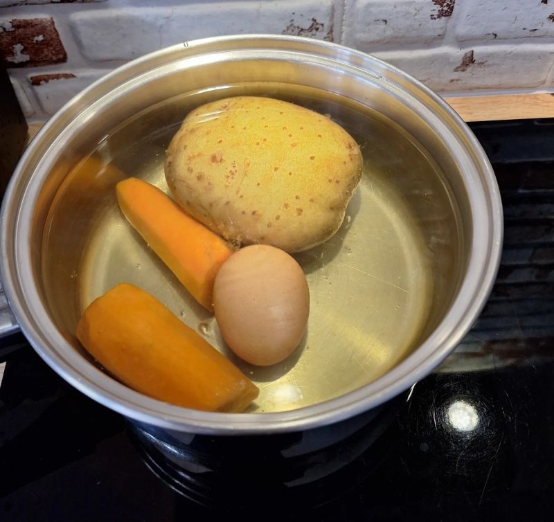 Potato, carrot and egg cooking in a saucepan for ensaladilla rusa