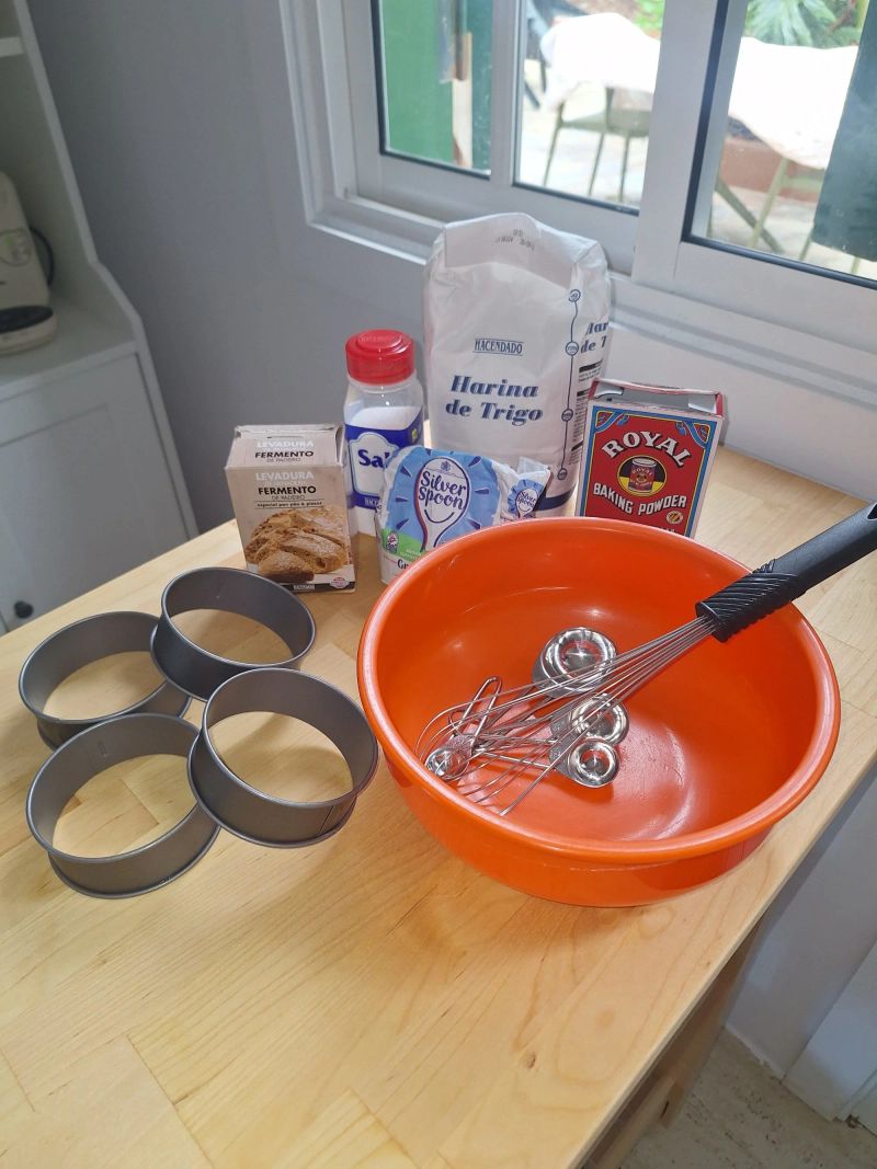 Flour, yeast, baking powder, sugar, salt, crumpet rings, bowl and whisk for making English crumpets