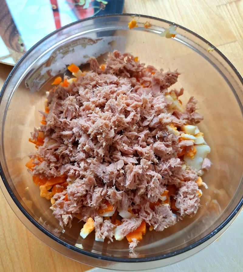 Flaked tuna added to chopped potato, carrot and egg for Russian salad