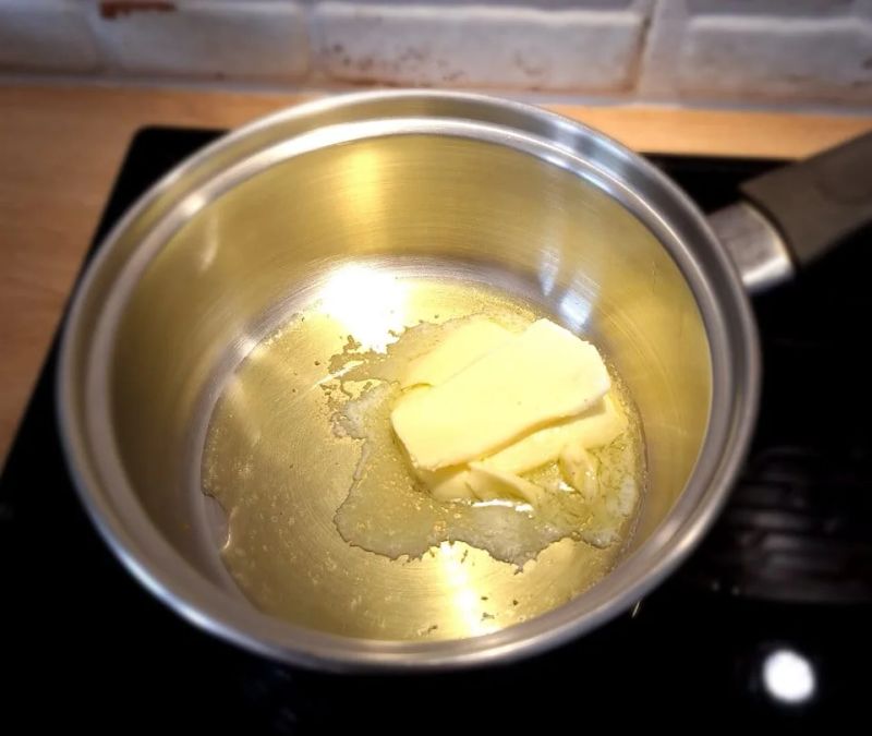 Unsalted butter melting in a saucepan for the cheesecake biscuit base
