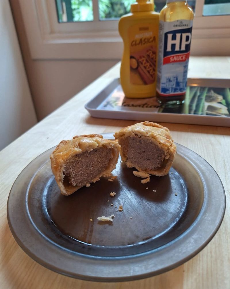 Mini pork pie cut in half to show the seasoned pork filling inside the crisp golden pastry.