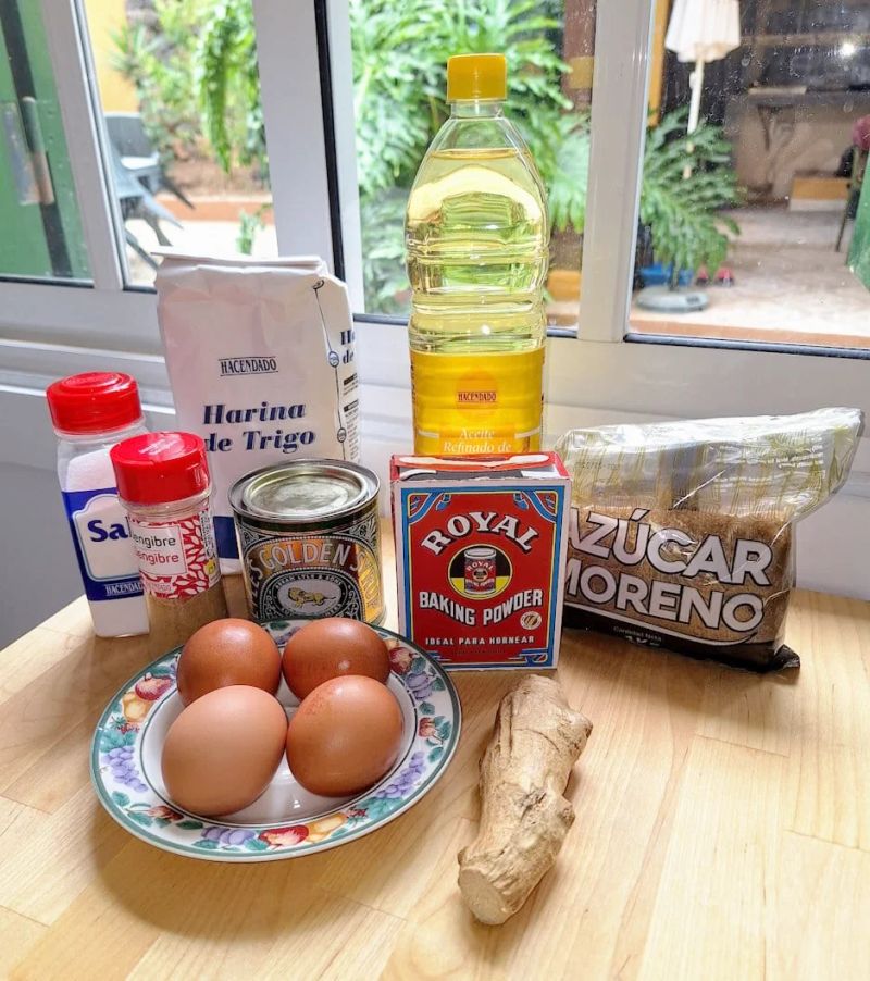 Ingredients for homemade ginger cake including flour, brown sugar, eggs, fresh ginger, golden syrup, vegetable oil, baking powder and ground ginger.