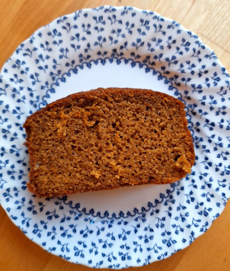Slice of homemade ginger cake on a patterned plate, showing the soft, moist texture and fine crumb.